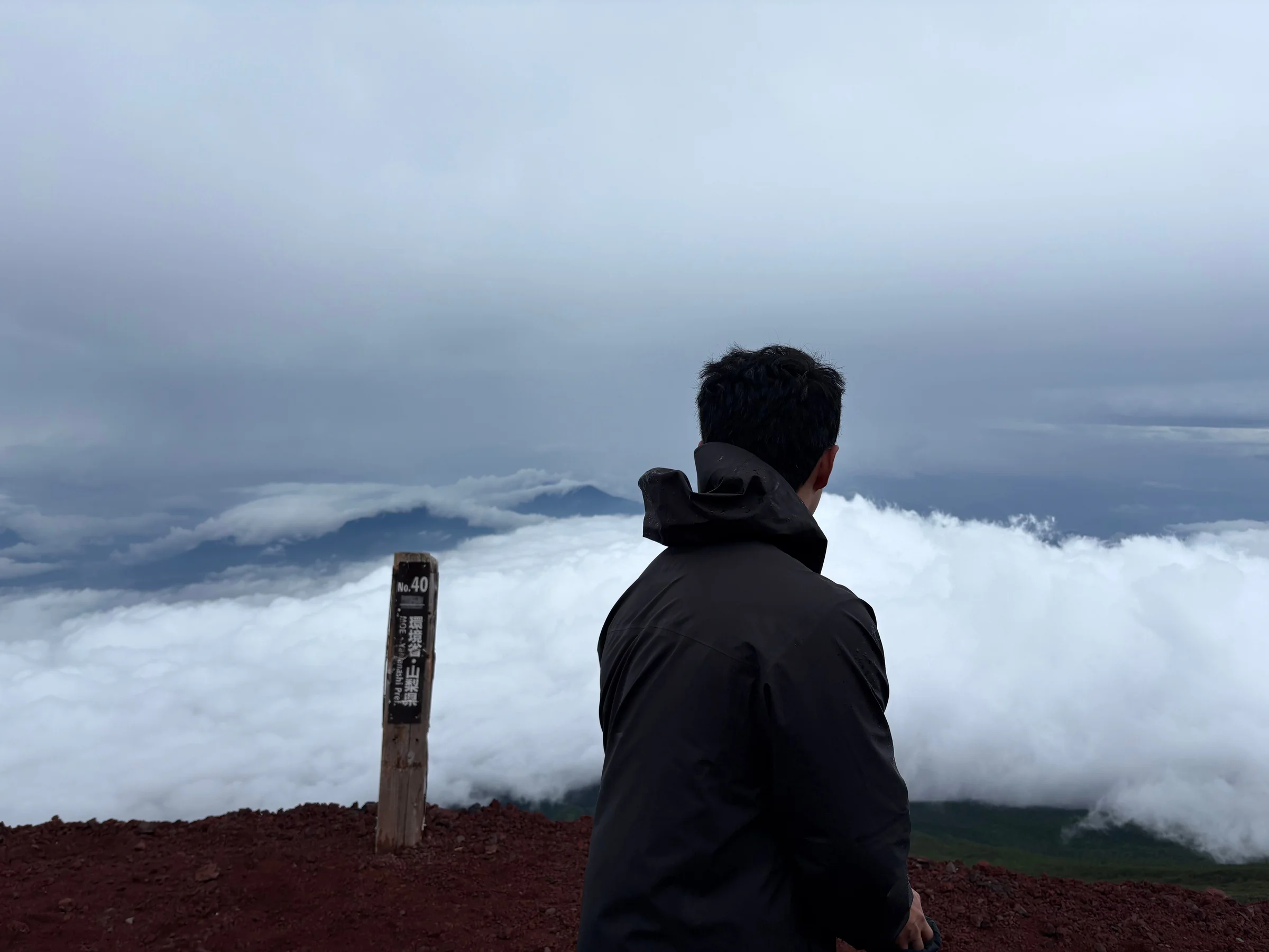 Looking out over a sea of clouds from a trail marker on Mt. Fuji