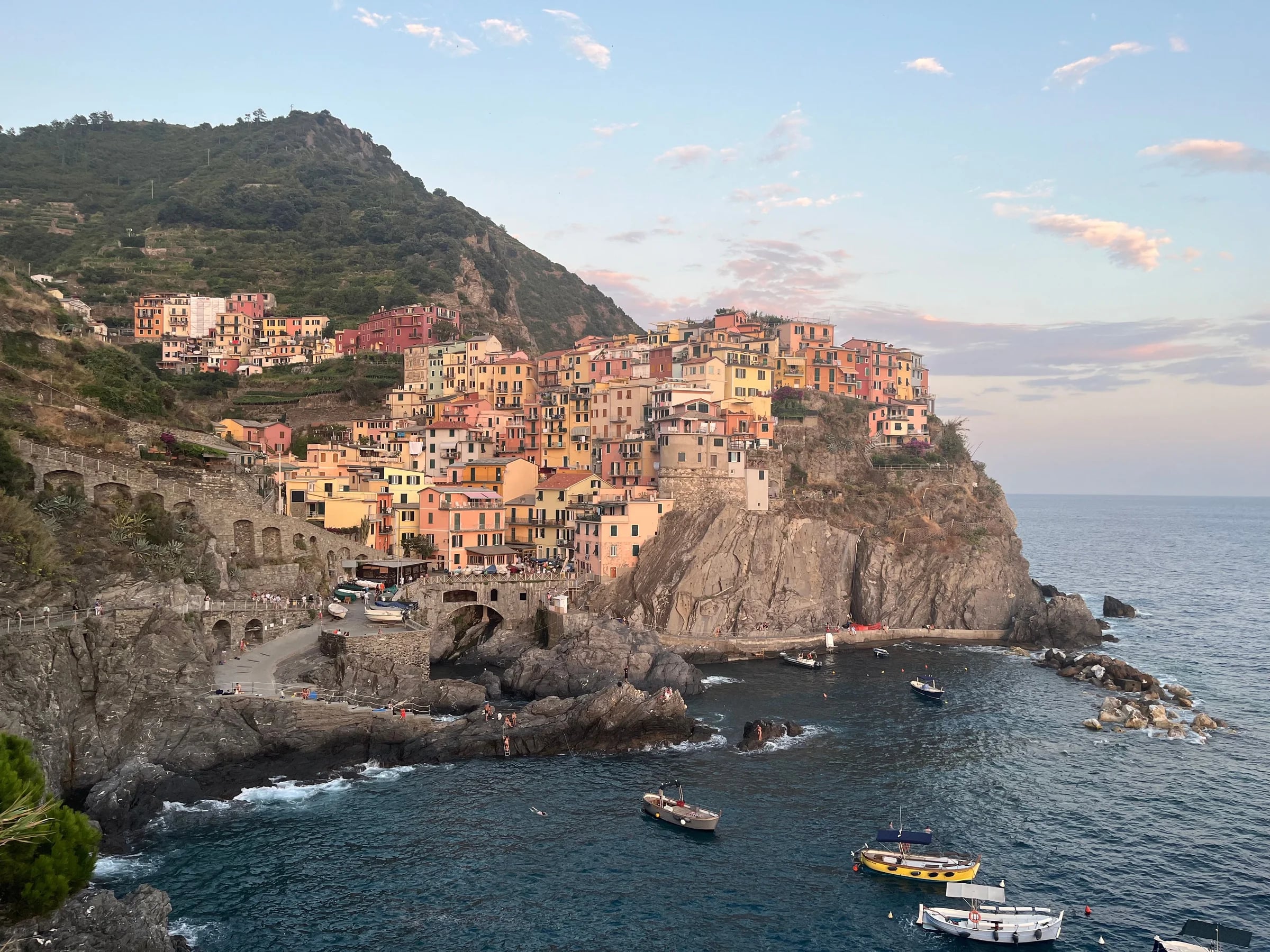 Pastel houses stacked on a cliff above the sea in Manarola at sunset